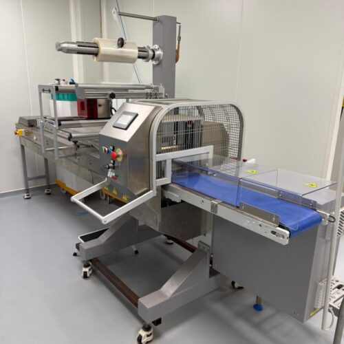 Ensacheuse horizontale flowpack IPS FAR-E d'occasion avec convoyeur d'alimentation à taquets pour biscuits et viennoiseries.